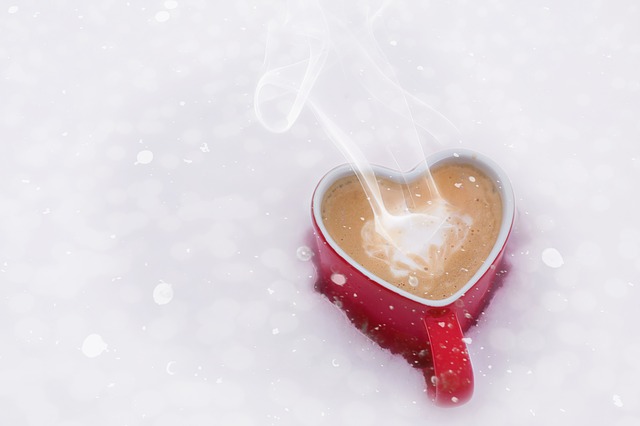 День святого Валентина - красная кружка с кофе в форме сердечка стоит в снегу